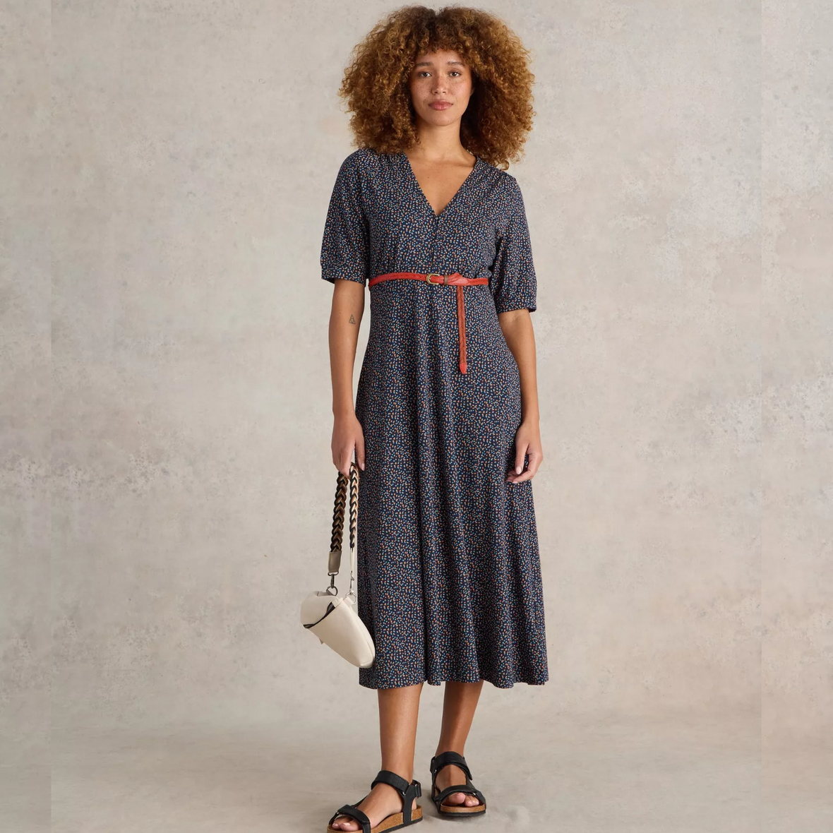 female model wearing whitestuff jeresey dress in navy print with arms down by side