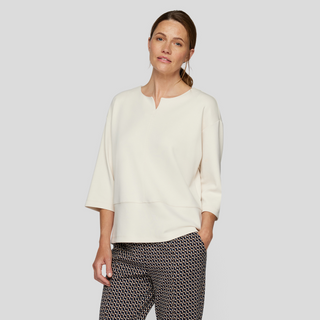 female model wearing rabe top in vanilla colour with hand in pocket