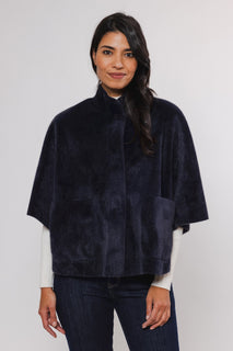 female model looking at camera wearing rino pelle faux fur cape in navy colour 