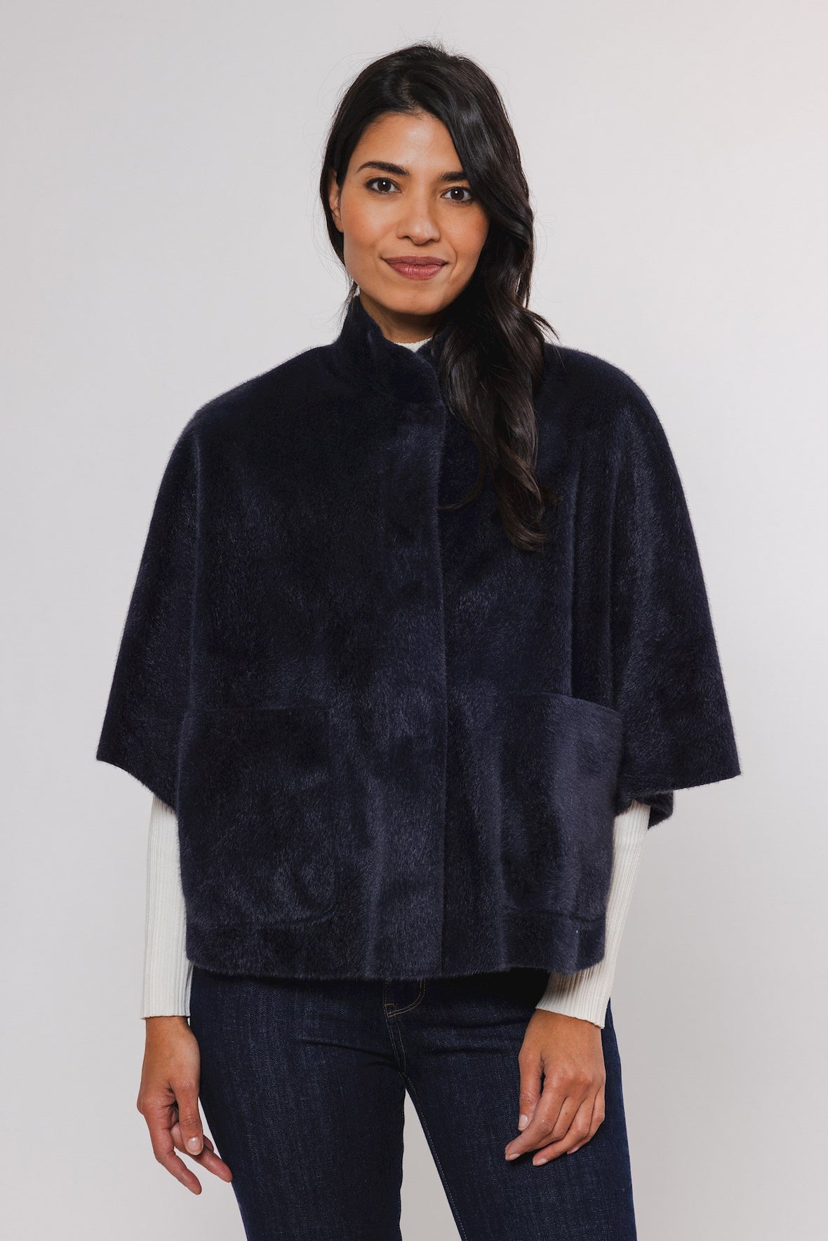 female model looking at camera wearing rino pelle faux fur cape in navy colour 